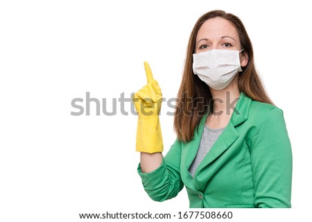 Portrait of young woman with face mask and yellow gloves pointing finger up, isolated on white background