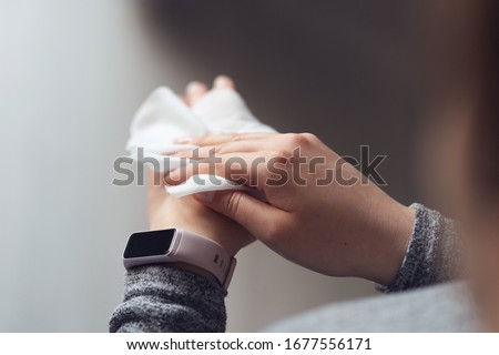 Close up on midsection of young caucasian woman hands wiping using white alcohol tissue cleaning napkin disinfection from virus and bacteria in day at home or office high angle view Royalty-Free Stock Photo #1677556171