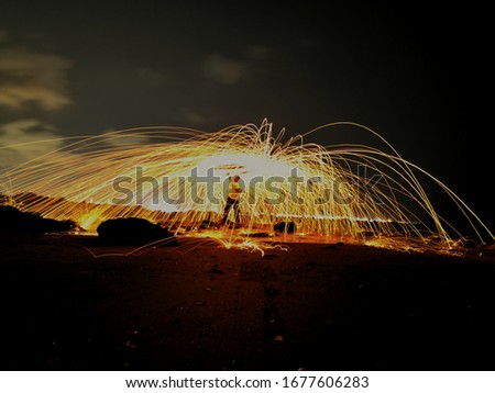 Abstract,Long exposure of swirling flame sparks arcing in circle at the night is black background.