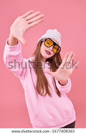 Bright teen girl in modern clothes and sunglasses on a pink background. Youth style, fashion. Studio portrait. Copy space.