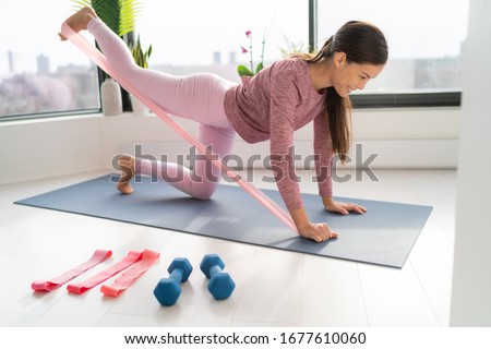 Resistance band fitness at home Asian woman doing leg workout donkey kick floor exercises with strap elastic. Glute muscle activation with kickback for thighs cellulite. Royalty-Free Stock Photo #1677610060