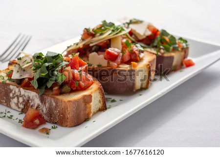 A closeup view of a plate of bruschetta, in a restaurant or kitchen setting.