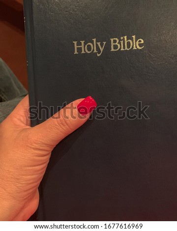 A woman's hand holding a Holy Bible.