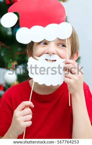 happy little boy plays with Christmas masks of Santa