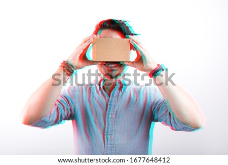 studio shot of a young, smiling model looking through cardboard virtual reality (VR) headset, isolated on white with 3D anaglyph effect, glitch art. 