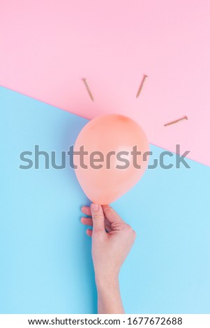 Creative top view on pastel orange balloon in womens hand and golden nail on colourful background with copy space. Concept of blog, creative idea, party. Template of brainstorm idea, create your text