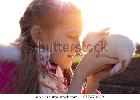 girl and rabbit on the lawn in the garden at sunset
