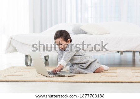 Asia cute baby playing laptop in whitebedroom