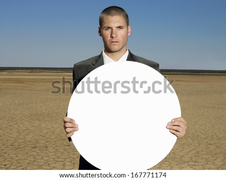Portrait of young businessman holding blank sign