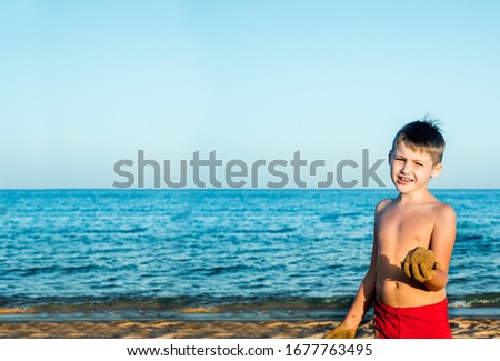 Sea holidays. Cute boy on the beach plays with sand. Casts a sand castle and cakes. sunset, blue sky and relax travel concept. copy space.