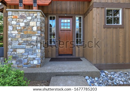 Front door with wooden elements and glass in natural style brown mountain home.