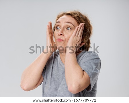 Elderly woman in a gray shirt scared face