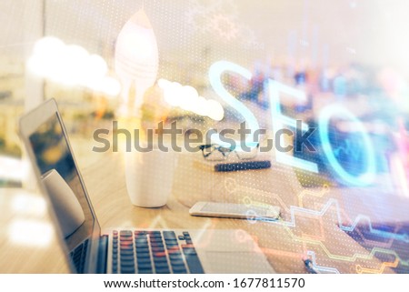 Multi exposure of table with computer and seo drawing hologram. Search optimization concept.