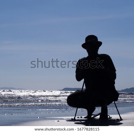 The silhouette of young man taking pictures on the sea beach
