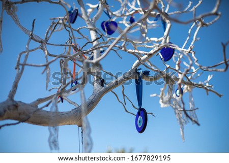Close up view of evil eye beads (nazar boncuğu) are hanging down from a tree in Antalya, Turkey. There is only blue sky in back. 2020