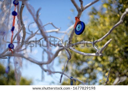 Close up view of evil eye beads (nazar boncuğu) are hanging down from a tree in Antalya, Turkey. There is only blue sky in back. 2020