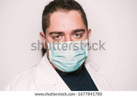 Medical stock photography wearing blue mask and white coat with green eyes.