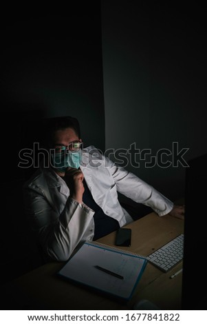 Stock photo of a doctor looking at the infinite sitting in his office. Photography from front view.