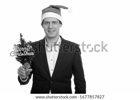 Happy handsome Caucasian businessman holding Merry Christmas tree