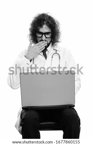 Studio shot of handsome man doctor using laptop looking shocked