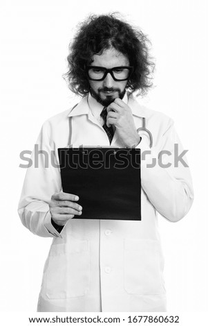 Studio shot of handsome man doctor reading on clipboard while thinking