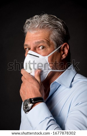 scary looking man wearing PPE,  fpp2 mask and holding it Royalty-Free Stock Photo #1677878302