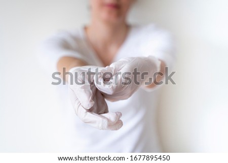 Unrecognizable female nurse explaining steps to properly take gloves to avoid contagious disease. Detail of plastic preventive gloves for protection of covid 19 corona virus. Healthy habits.