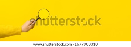 magnifier in hand  over yellow background, panoramic mock-up image Royalty-Free Stock Photo #1677903310