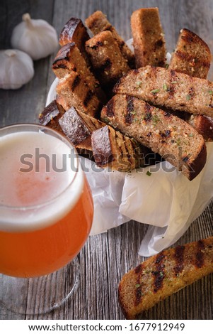 Grilled garlic bread with light beer on a wooden background.