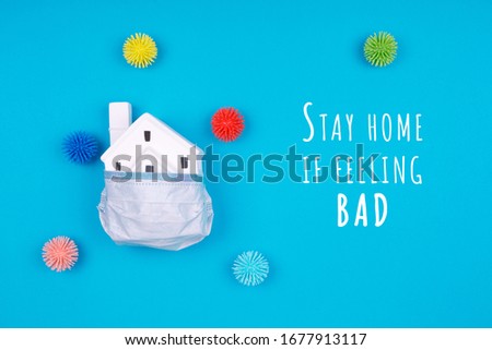 Cute house covered with medicine mask and plastic balls aka viruses on the blue background with Social Distancing wording. Epidemic, social isolation, coronavirus COVID-19 concept. Option with text Royalty-Free Stock Photo #1677913117