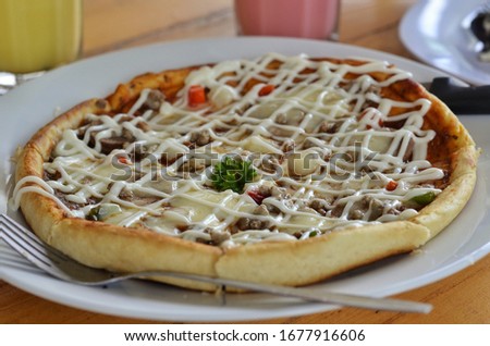 Thin crust italian pizza topped with minched beef, mozzarella cheese, and mayonnaise spread as condiment. 