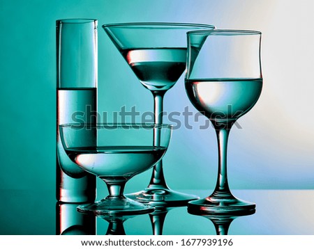 Different glass goblets on a turquoise background. Beautiful still life