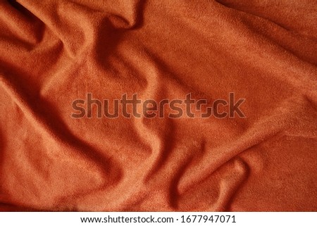 Draped bright reddish orange artificial suede fabric