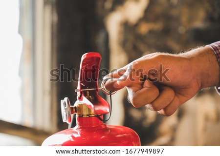 Close up hand Fireman using fire extinguisher fighting. Hand pulling pin of fire extinguisher