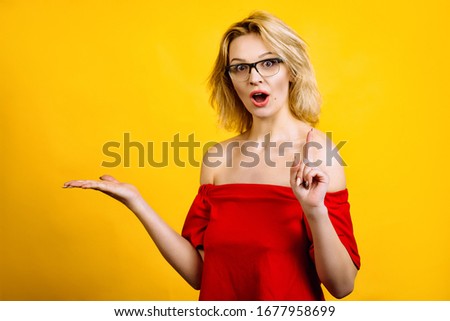 young woman shows with her hands. beautiful girl in glasses posing with hands. blonde in a red top.