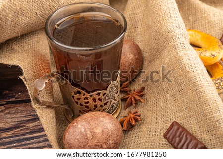 A glass of tea in a vintage Cup holder , chocolate gingerbread and chocolate on a background of textured fabric. Close up.