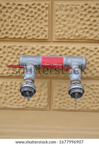 water pipe for fire protection on the facade of an old historic house for the distribution of hoses firefighter beige plaster with decorative pattern