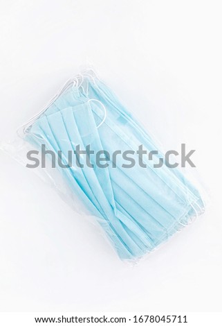 Disposable medical protective face mask. Blue masks pack. White background, isolated, top view. Pile of masks. Covid-19 protective measures.