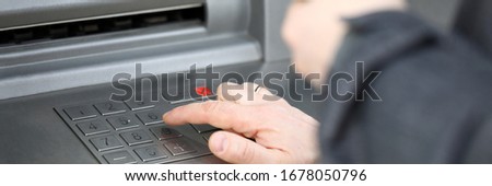 Close-up of man pressing pin code on cash machine outdoors. Person getting salary or pension. Credit card and atm. Money and financial stability concept