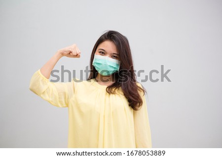 Portrait of a cheerful and healthy young woman asian wearing medical mask. Pandemic 2019 Coronavirus 2019-nCoV Concept. Royalty-Free Stock Photo #1678053889