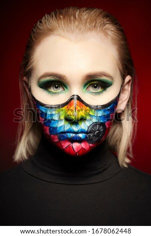 Pretty blonde young woman with painted mask on her face