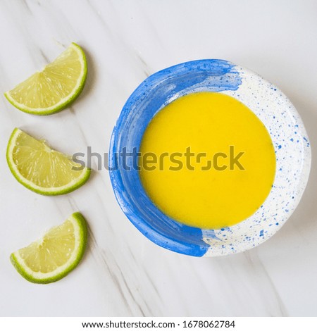 Food photography of mango and lime sauce in blue handmade ceramic and balnca on a marble table