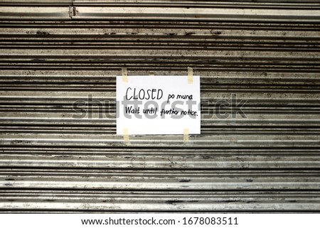 Photo of a CLOSED signage taped to a steel gate of a closed store because of community quarantine during the Covid 19 virus outbreak.