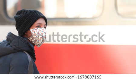 Young Afro-American during a viral epidemic on a city street with a homemade fabric face mask waiting for metro