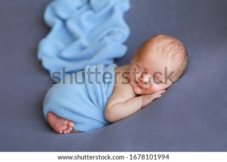 
Newborn baby on a blue surface. Newborn boy is smiling. Beautiful picture of a child. The baby is laughing. The child is wound up. Photoshoot of a newborn 