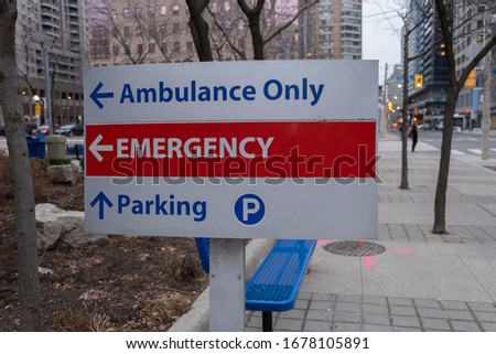 Sign in front of a hospital with directions to Ambulance trucks, emergency and parking. Health care and essential emergency medical services concept. Selective focus.