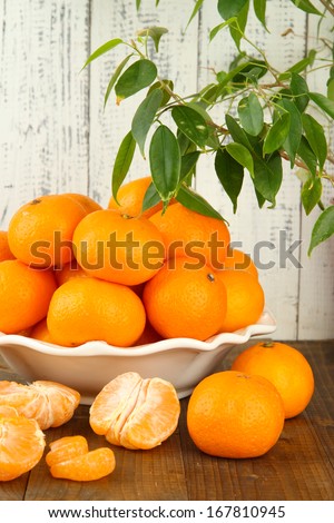 Ripe tangerines in bowl on table on wooden background