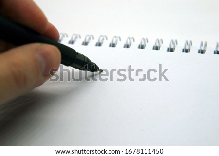 hand writes with a pen on a Notepad on springs