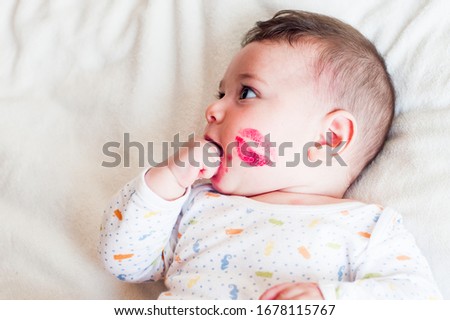 cute newborn baby with lipstick in his cheek