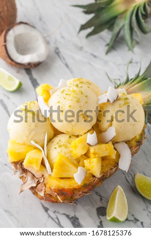 pineapple coconut ice cream or sorbet pina colada scoops served in pineapple with slices of pineapple and coconut, ice cream or sorbet on a marble table Royalty-Free Stock Photo #1678125376